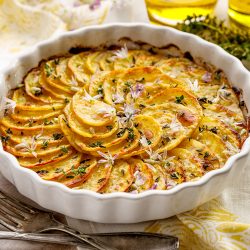 Scalloped potatoes, potato casserole with the addition of herbs and edible chives flowers in a ceramic baking dish - Does Corningware Contain Lead? [Inc. Blue Cornflower, Spice Of Life, & French White]