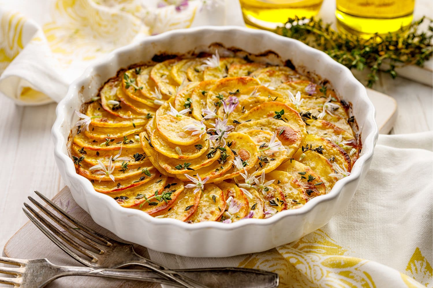 Scalloped potatoes, potato casserole with the addition of herbs and edible chives flowers in a ceramic baking dish