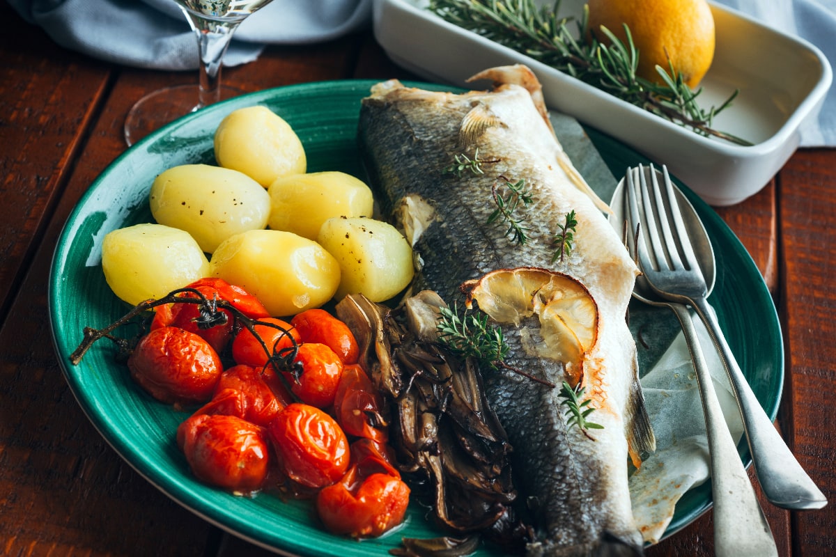 Sea bass baked with potatoes and tomatoes