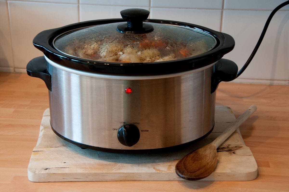 Slow cooker with wooden spoon on chopping board cheep winter cooking