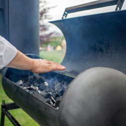 Smoker grill in home backyard, container with coal, smoke coming out of a smokestack, barbecue on green background, family patio, outdoor bbq party on op
