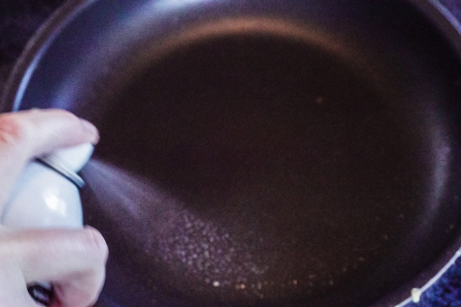 Step by step. Spraying cooking olive oil on frying pan to fry some pancakes.