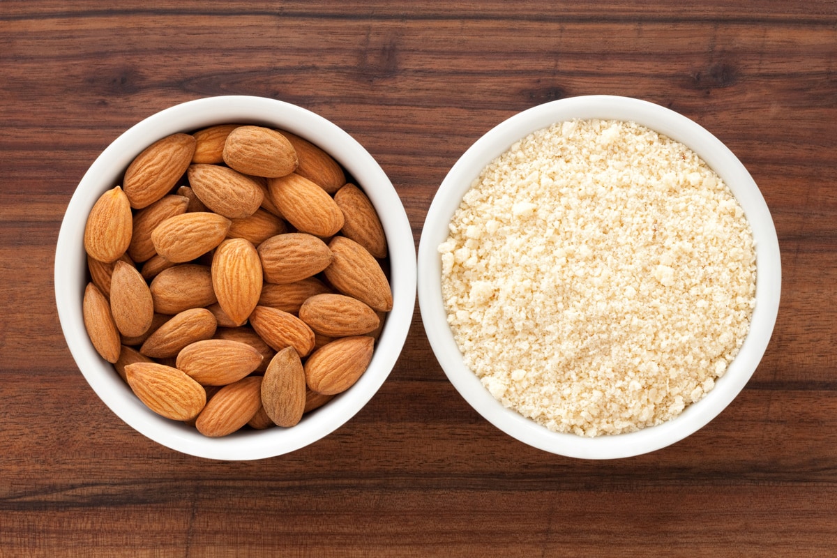 Two bowls containing almonds and almond flour for food processing concept