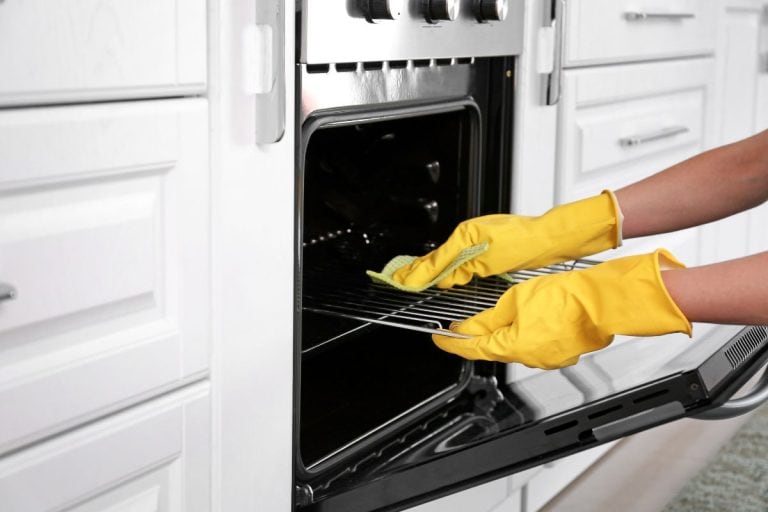 Woman cleaning oven in kitchen. - How Long Does Oven Self-Clean Take?