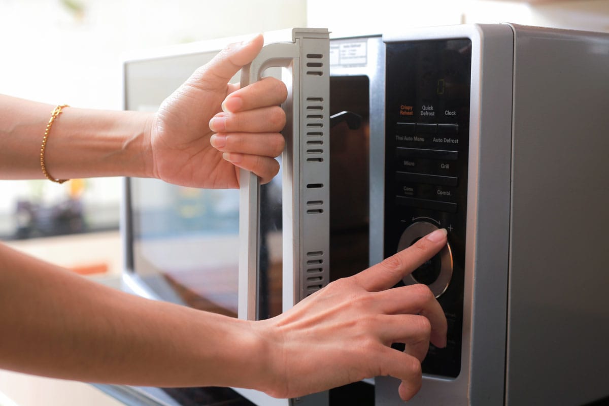 Woman's Hands Closing Microwave Oven Door And Preparing Food in microwave