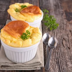 cheese souffle with a two spoon on a wooden table, How To Keep A Souffle From Deflating