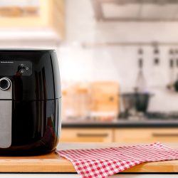 An electric Air Fryer on table with blurred kitchen background. Lifestyle of new normal cooking. - Why What To Do