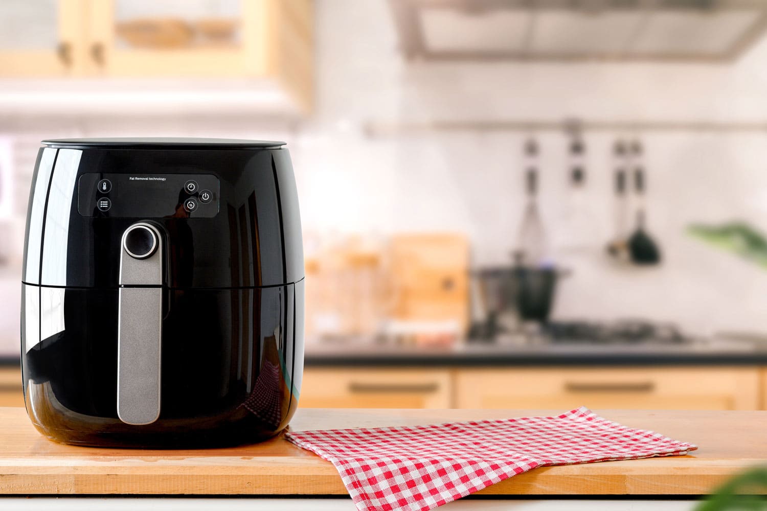 An electric Air Fryer on table with blurred kitchen background. Lifestyle of new normal cooking. 