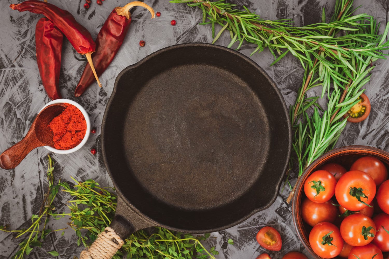 Cast iron pan on concrete background with red ripe tomatoes and red pepper 