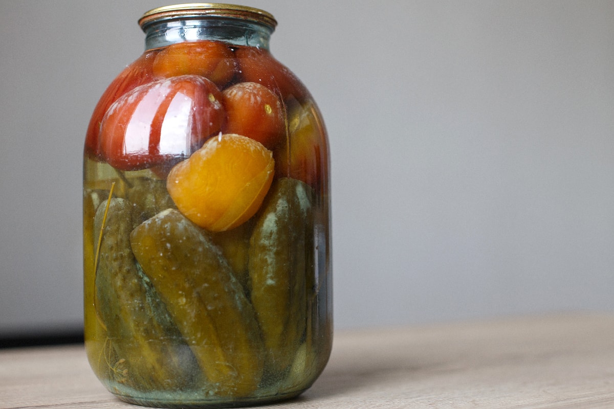 Glass jar with homemade pickled tomatos and cucumbers with white fungus and mold