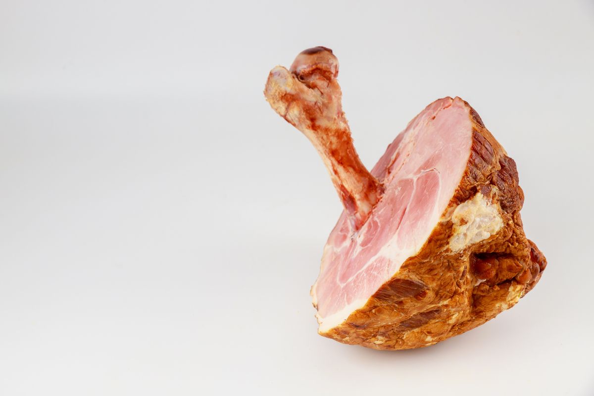 Honey glazed pork ham with big bone on white isolated background. 