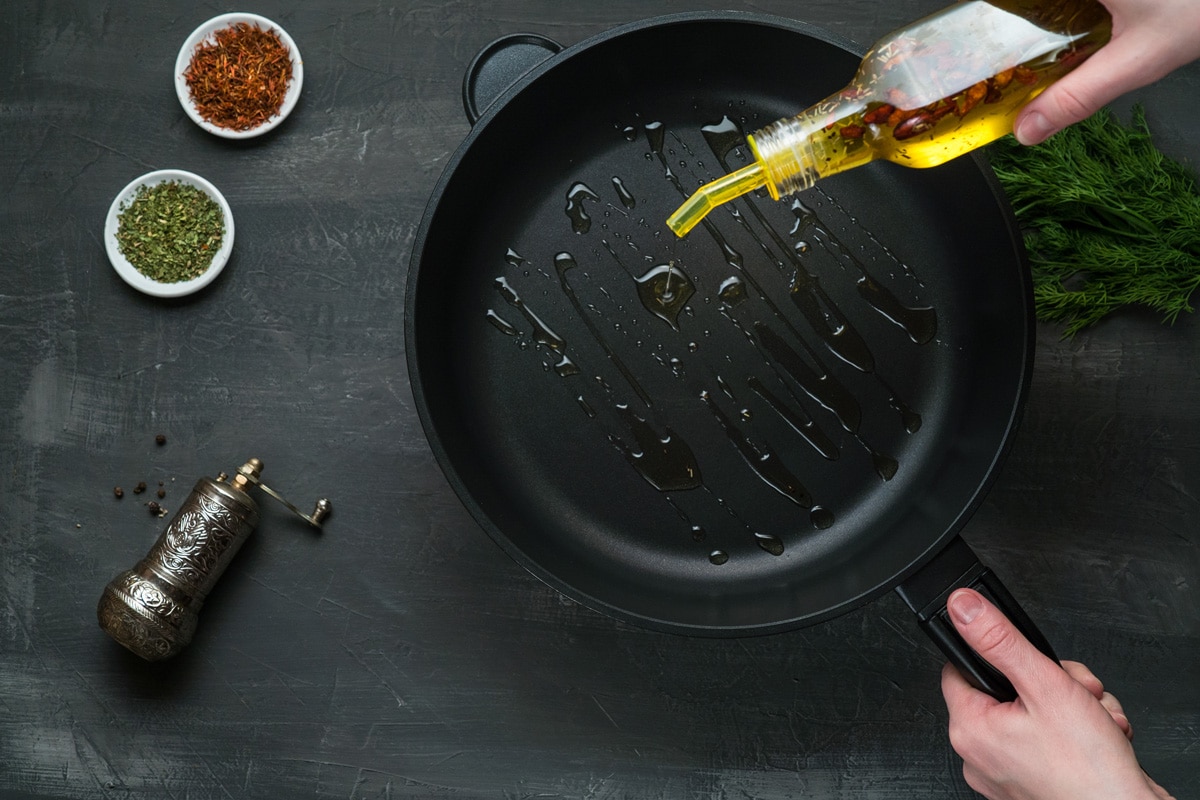 Man pouring cooking oil on the frying pan