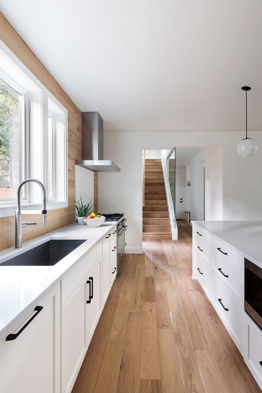 Modern Galley kitchen with wooden laminated flooring, white cabinets and white painted walls