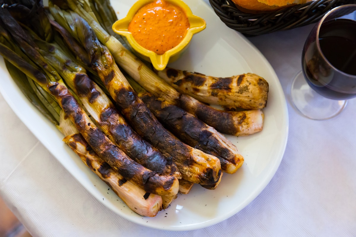 Roasted Calcots onions served on plate with Romesco sauce served on a plate