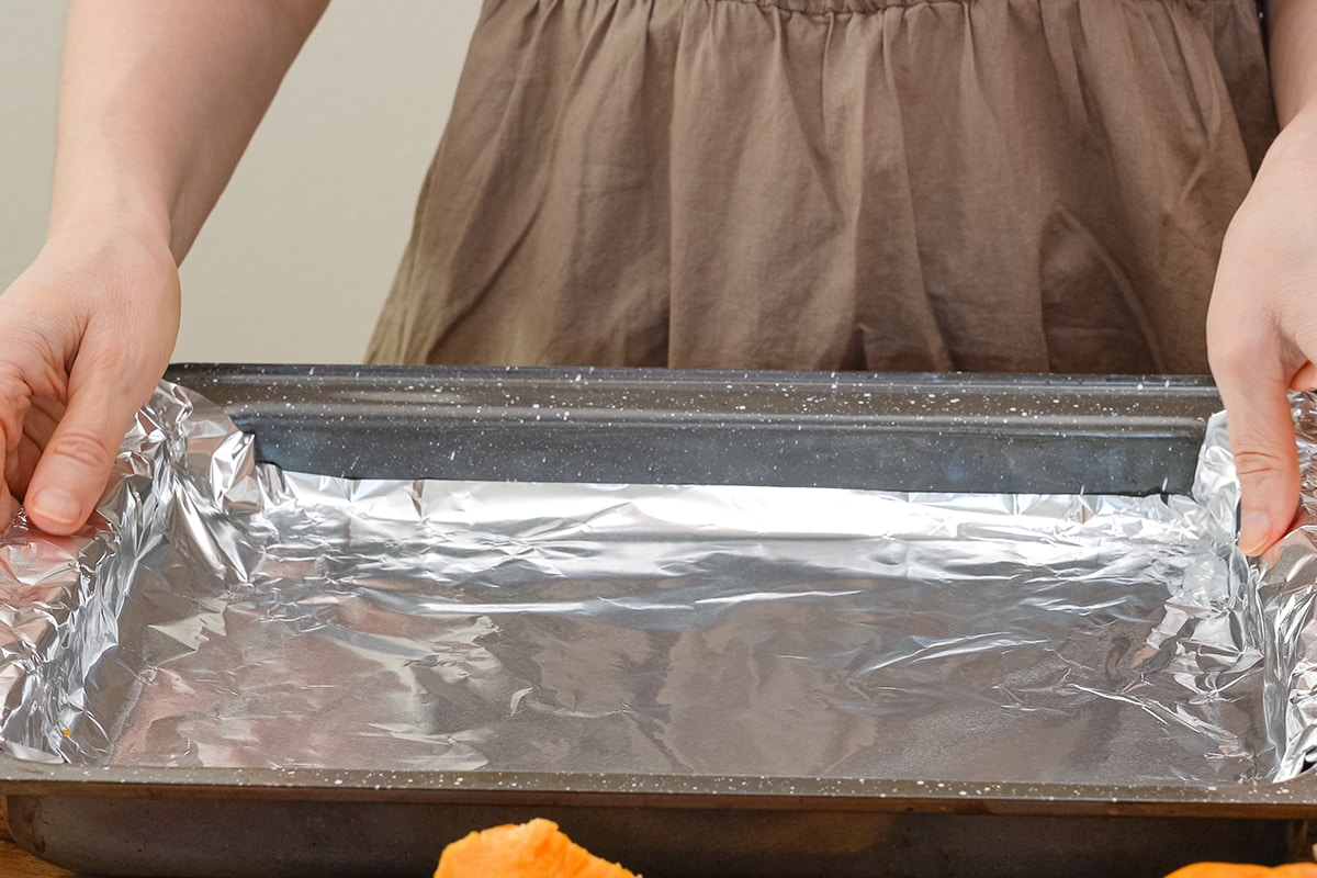 Woman hands placing aluminum foil on baking pan