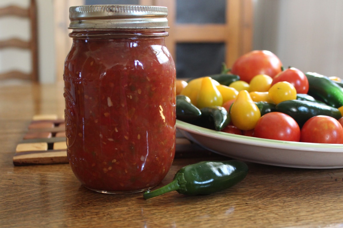 home canned salsa in glass jar with tomatoes and peppers 