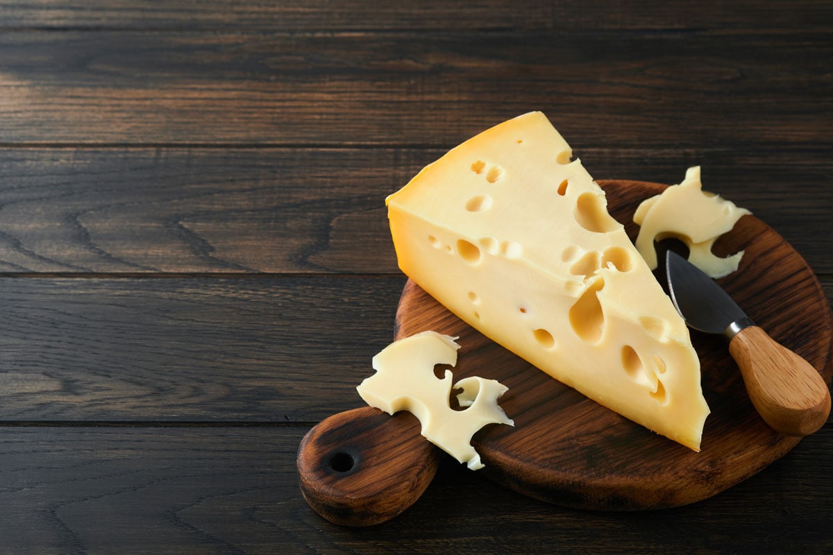 A big slice of Swiss cheese on a cheese board, Does Swiss Cheese Melt?