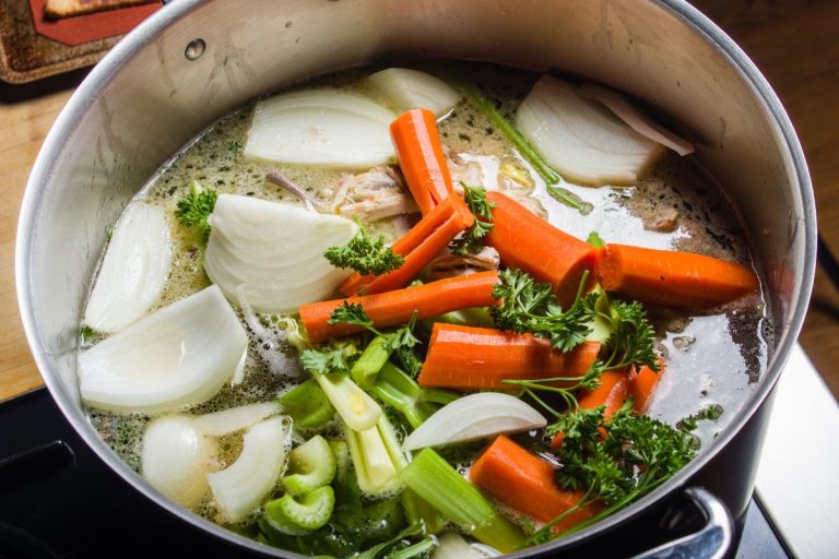 A large stock pot on a stove with vegetables cut for making soup. - How To Tone Down Celery Flavor In Cooking