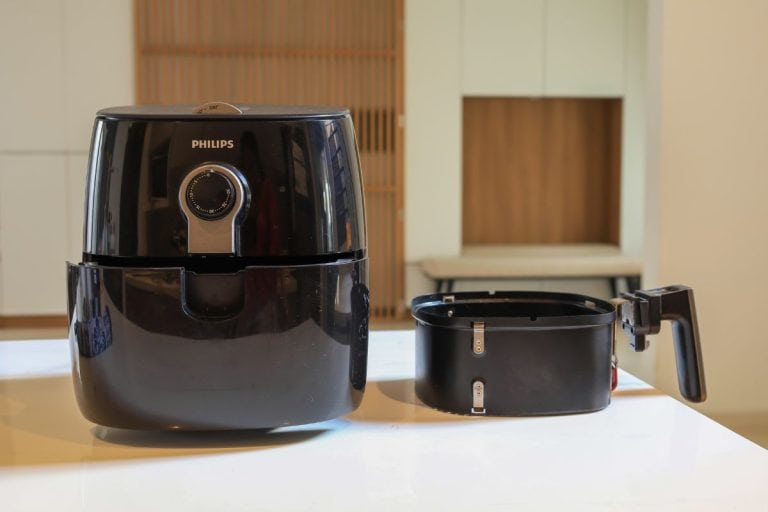 An electric Air Fryer on table with blurred kitchen background. Lifestyle of new normal cooking. - How Often To Clean An Air Fryer? [Do You Have To Wash It After Every Use?]