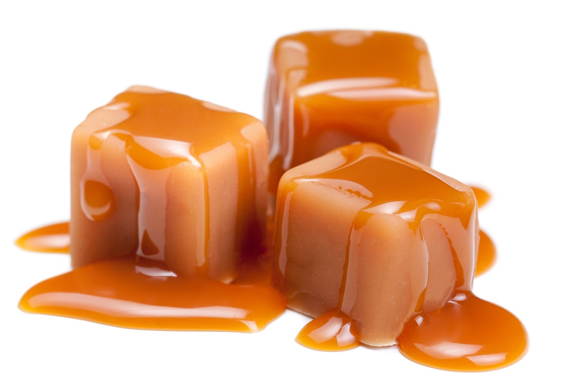 Caramel candies with caramel sauce isolated on a white background close up.