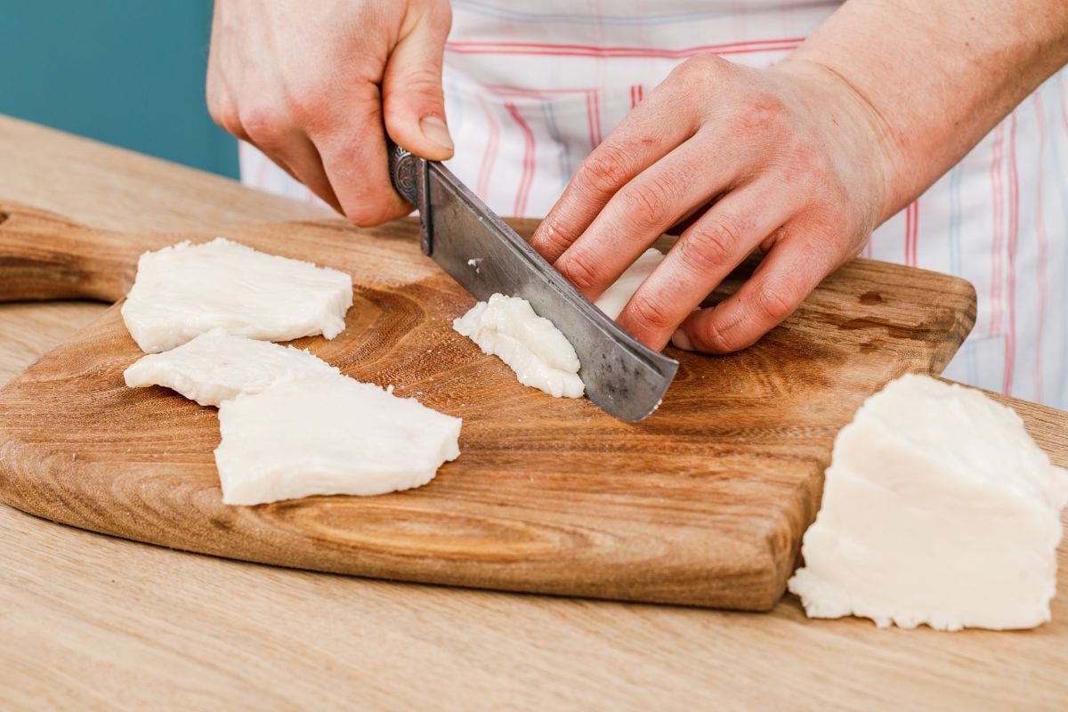 Cook cuts raw pork fat into small pieces on a wooden cutting Board. - Should You Reuse Beef Tallow