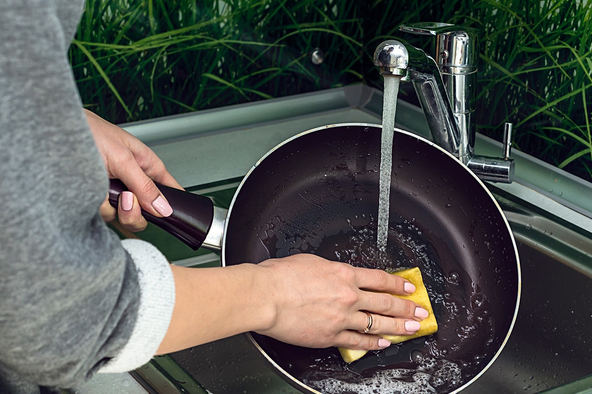 Female hand washing frying pan