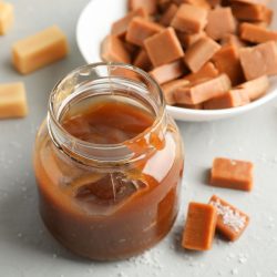 Glass jar with salted caramel and candies on grey background, close up. - Can You Melt Butterscotch Hard Candy?