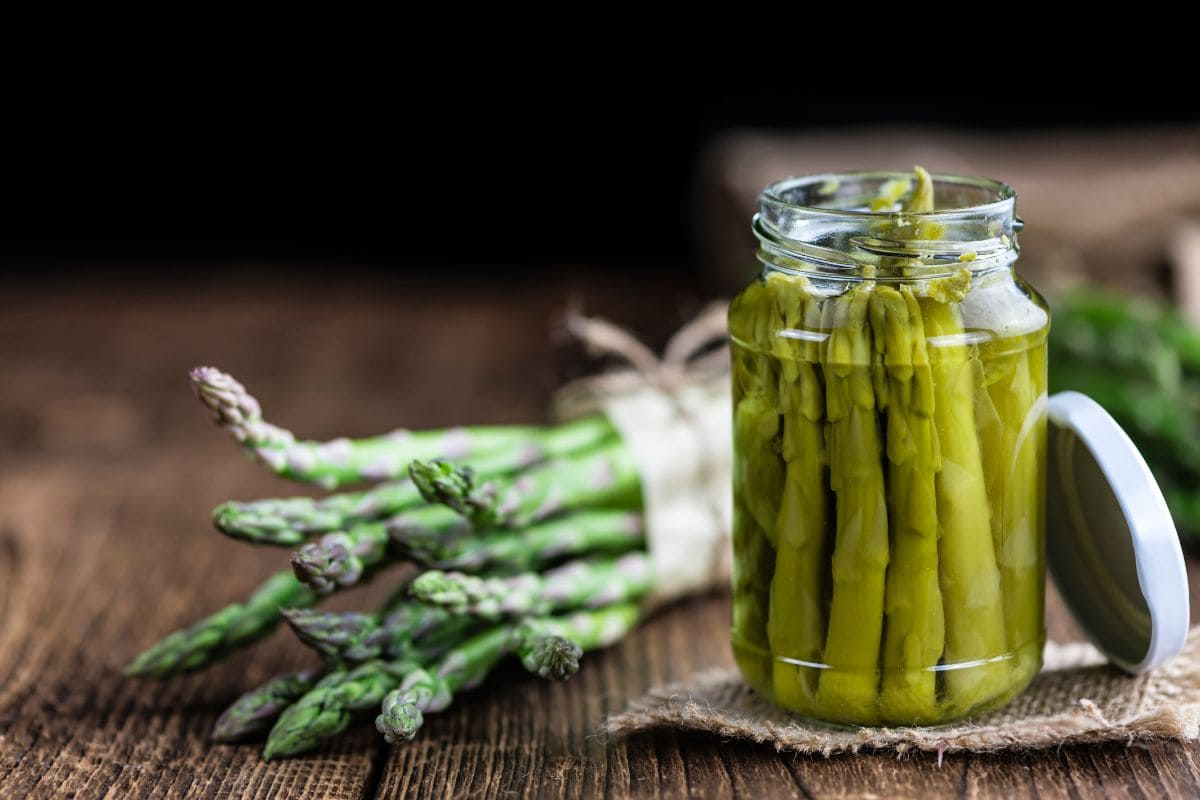 Green Asparagus (preserved) on an old wooden table (selective focus)