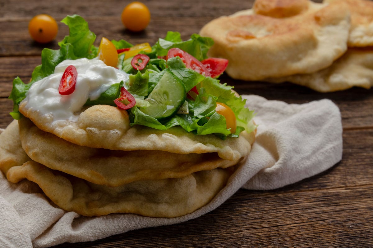 Navajo fried bread with green salad and yougurt on wooden
