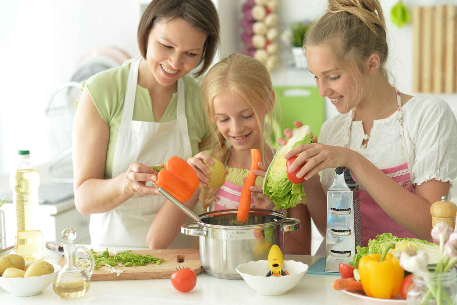 Portrait of cute girls with mother cooking in kitchen 