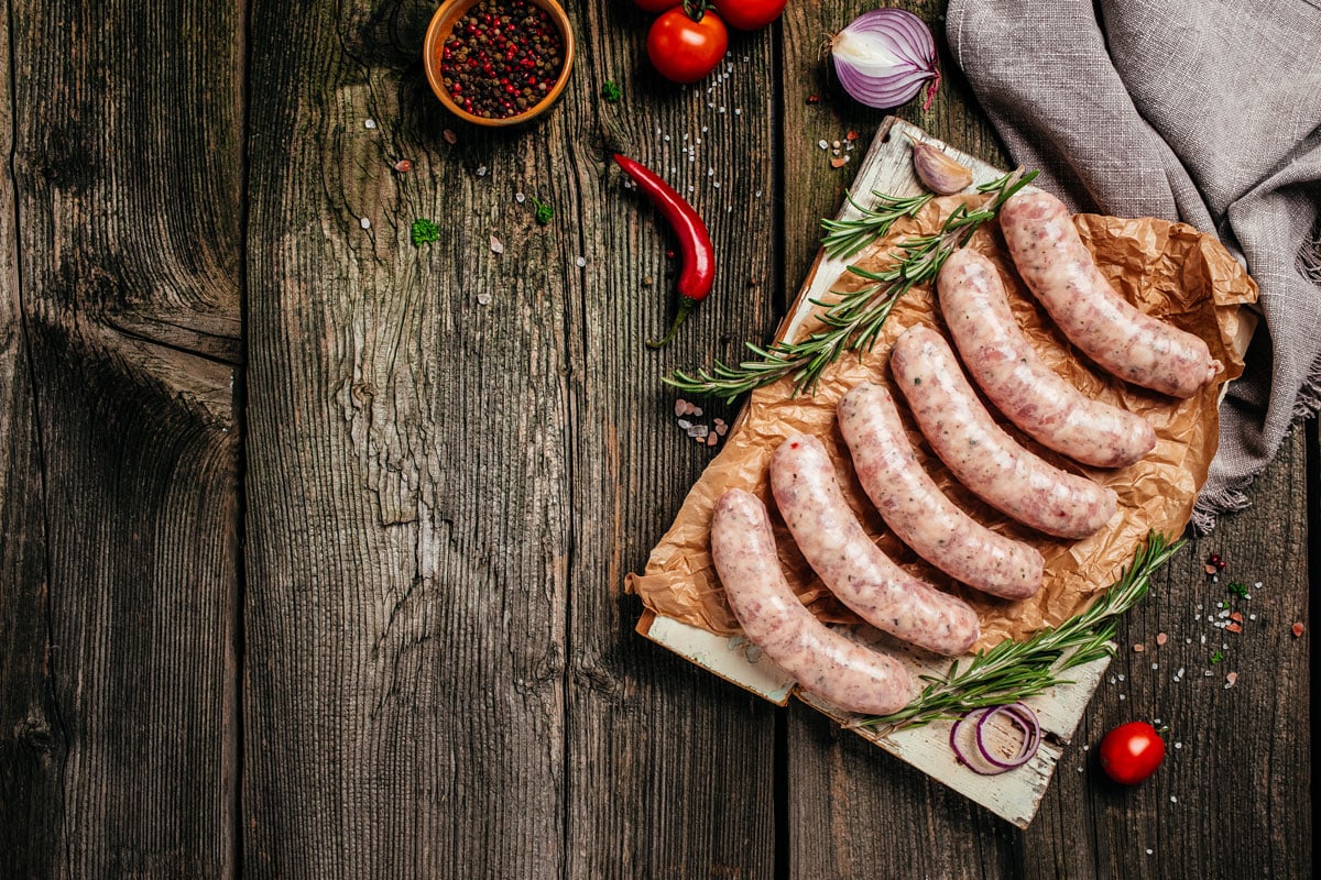 Raw stuffed sausages in cookware on a wooden