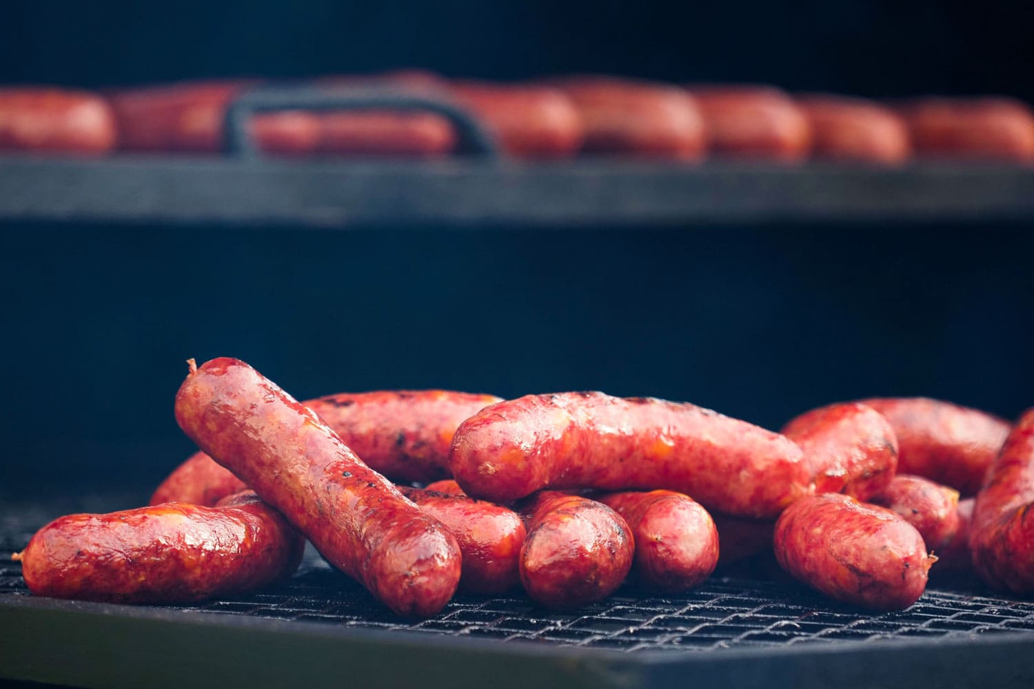 Sausages are prepared in a multi-tiered grill, smokehouse. Smoked sausages 