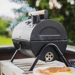 Small black smoker grill on the wooden table, Can You Put Glass Or Pyrex In A Smoker?