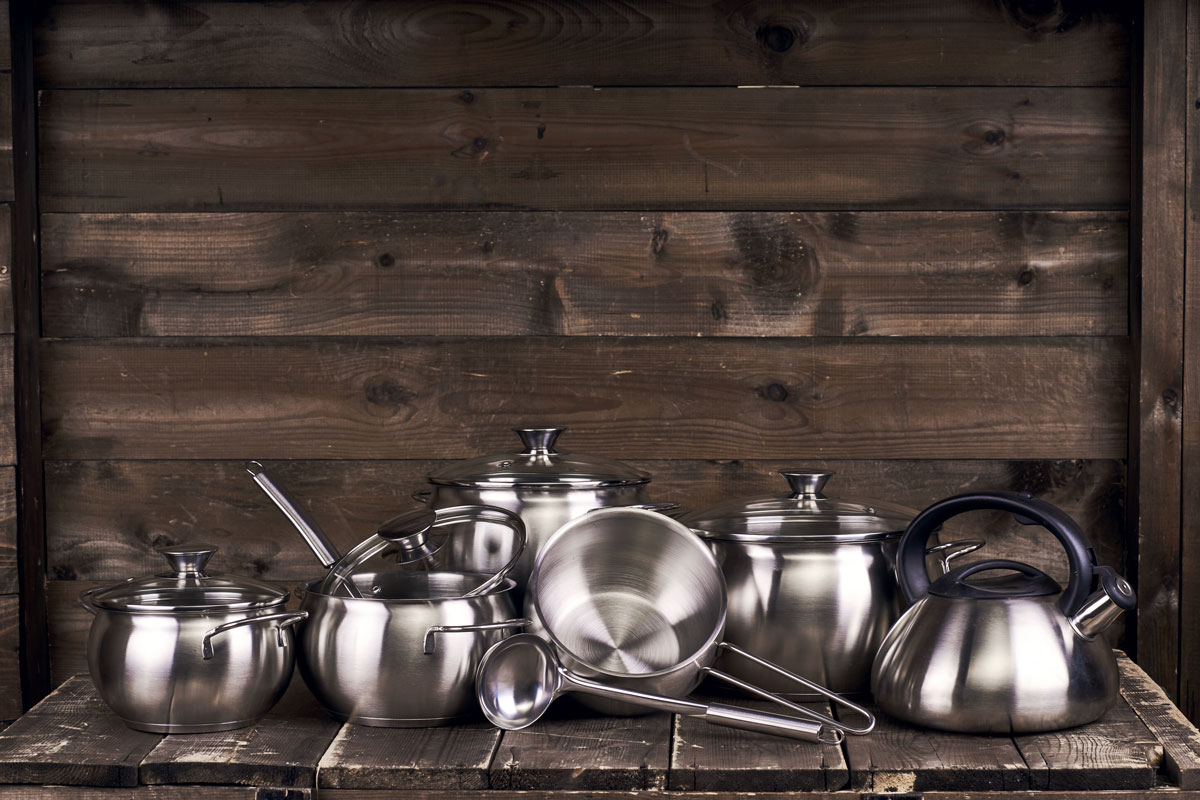 Stainless steel pots in the wooden table with a wooden background