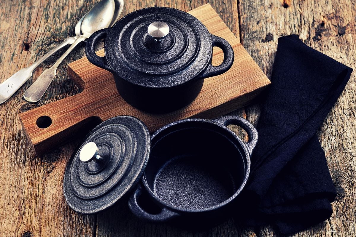 The small cast iron pan and cutting board on wooden background. Vintage style.