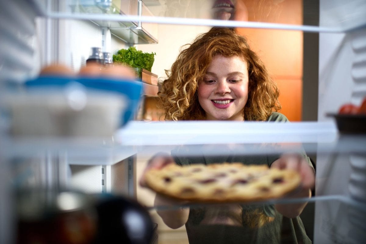 Woman taking sweet pie out of the refrigerator