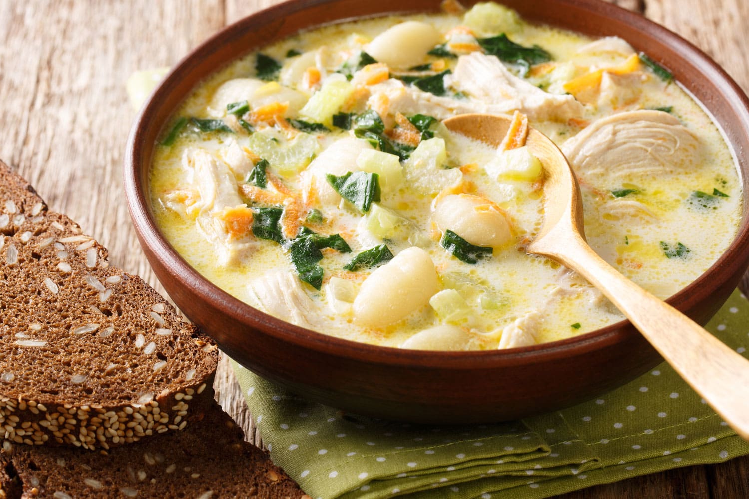 cream soup with gnocchi, chicken and spinach served with bread close-up in a bowl on the table. Horizontal 