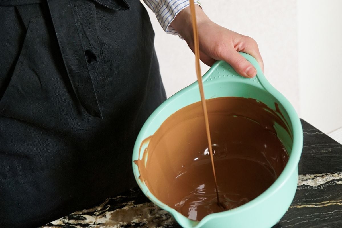woman stirs chocolate for making homemade chocolates. Candy making, pastry production, bakery, dessert concept.