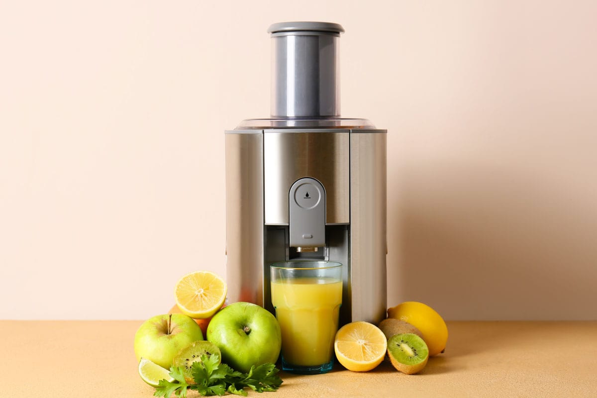 Modern juicer with fresh fruits on table