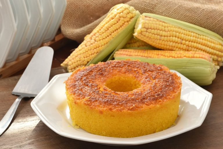 The corn cake in a plate on a wooden table with corn cobs and a wooden pot. - How To Grind Corn Without A Grinder