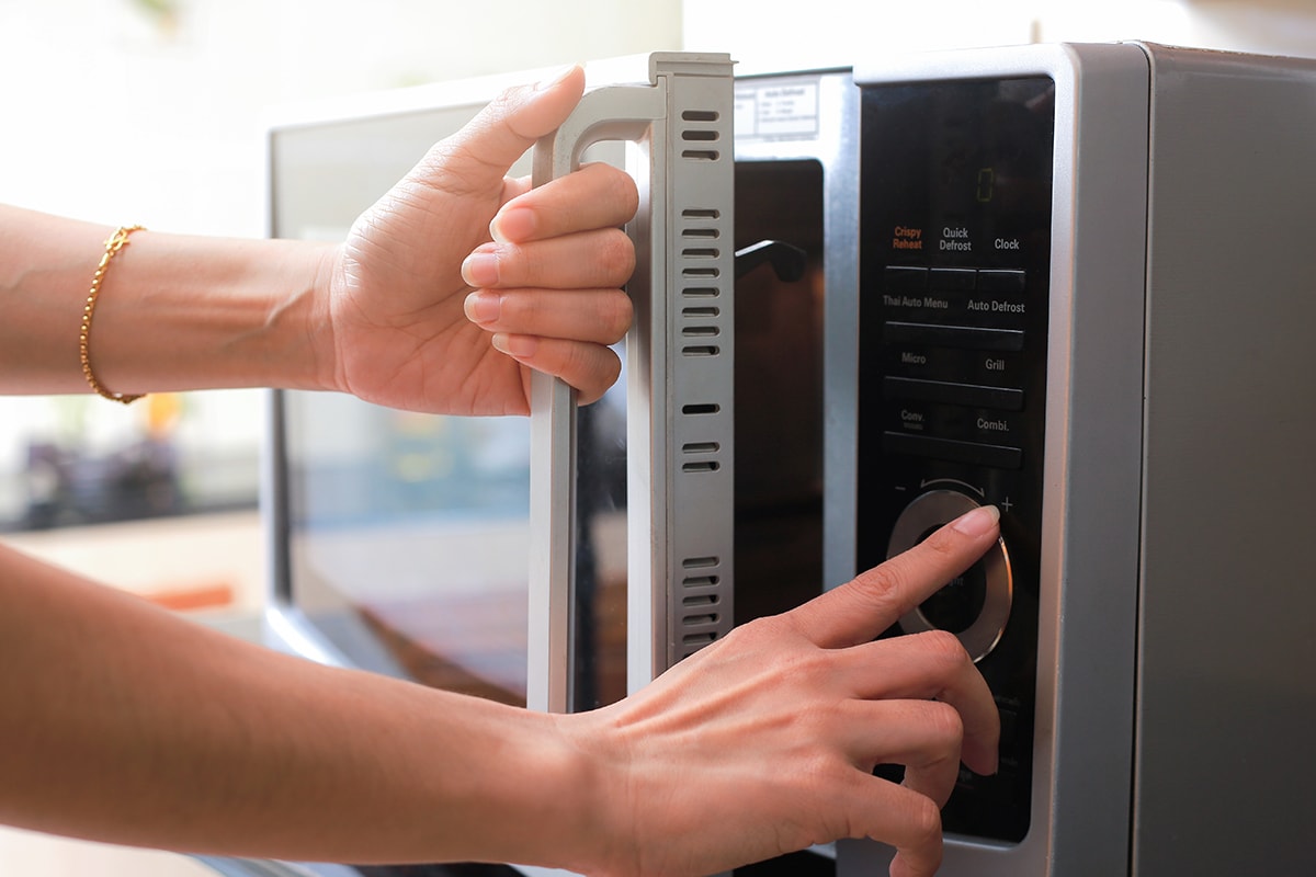 Woman's hands closing microwave oven door