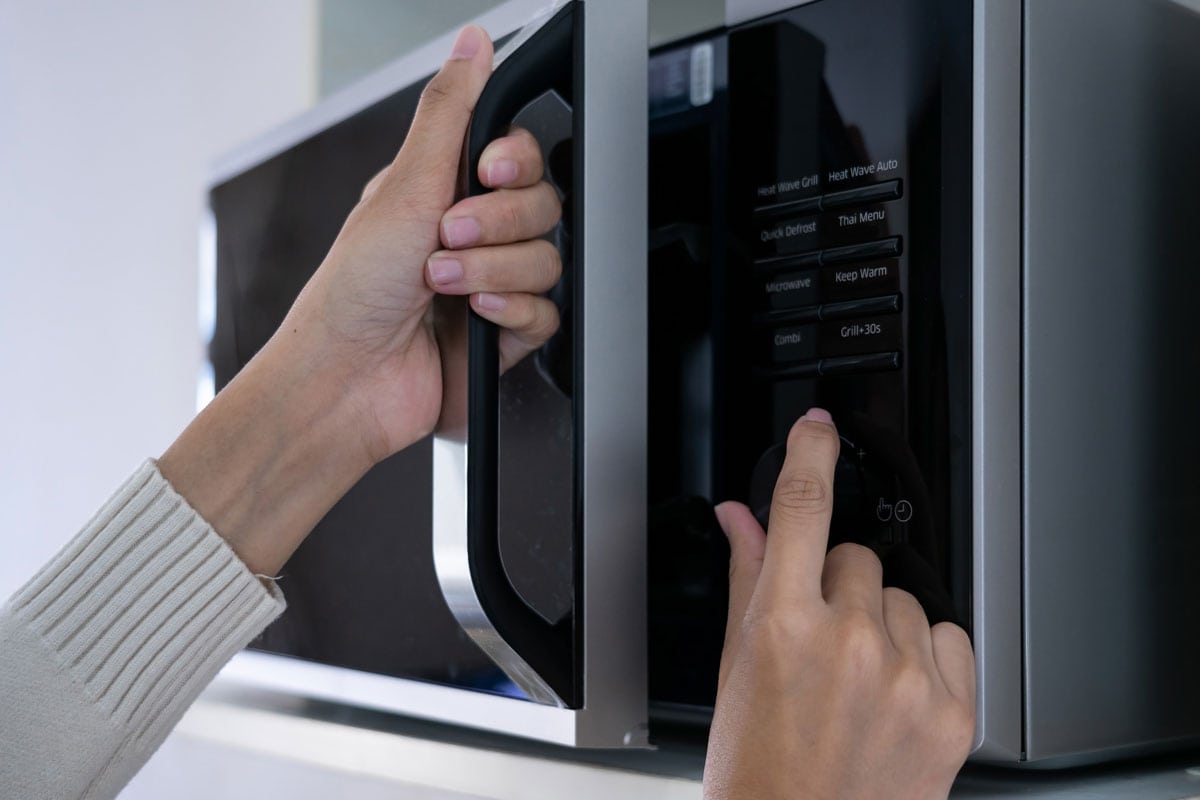 womans hands closing microwave oven door