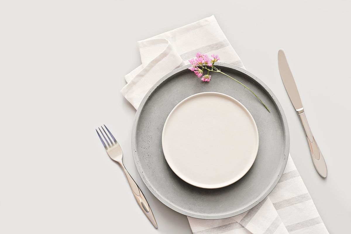 Empty grey plates on a table with fork and knife