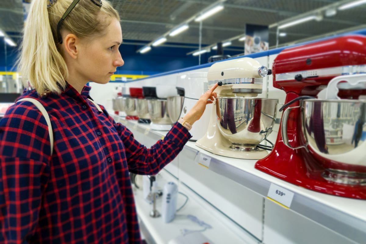 young woman choosing new kitchen mixer in household appliances store