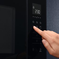 Hand sets time with circle button to heat food of microwave oven in kitchen room at home. - How To Set The Clock On An LG Microwave