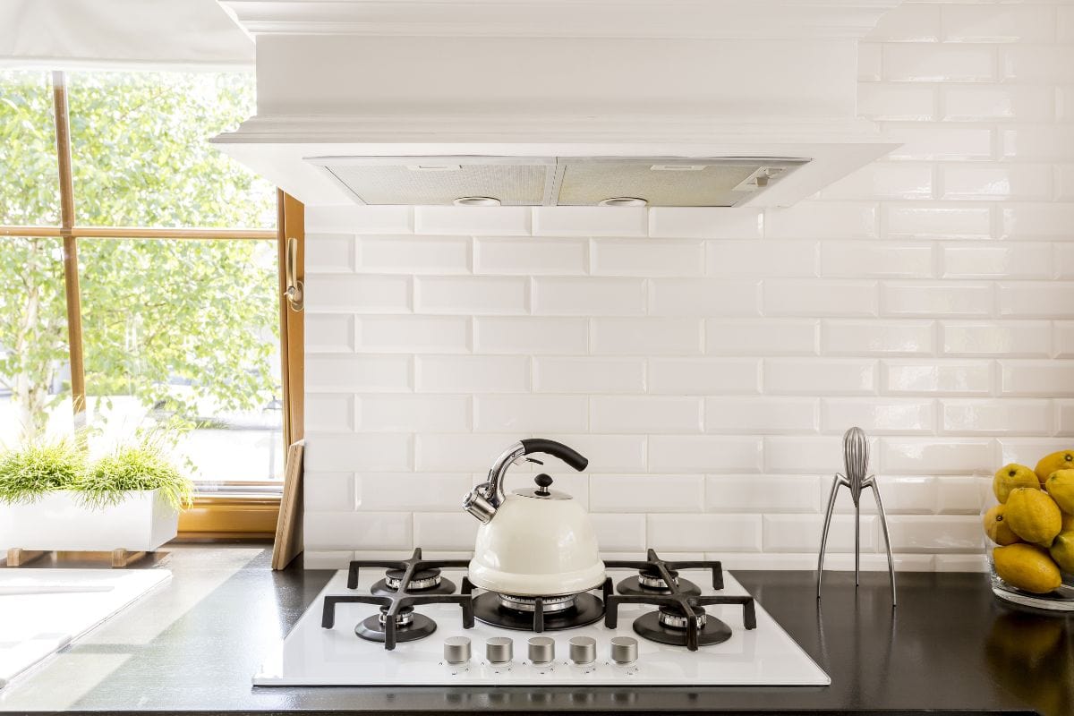 New style kitchen with dark worktop, white gas cooker and decorative brick backsplash