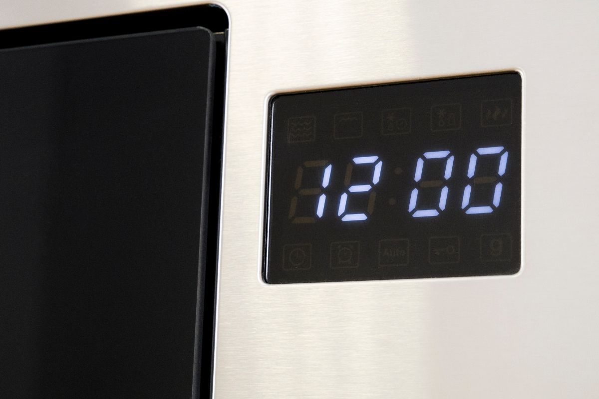 Digital Clock of microwave oven. Front panel of modern metalic microwave , blue indicators. Modern design in details. Household appliances.