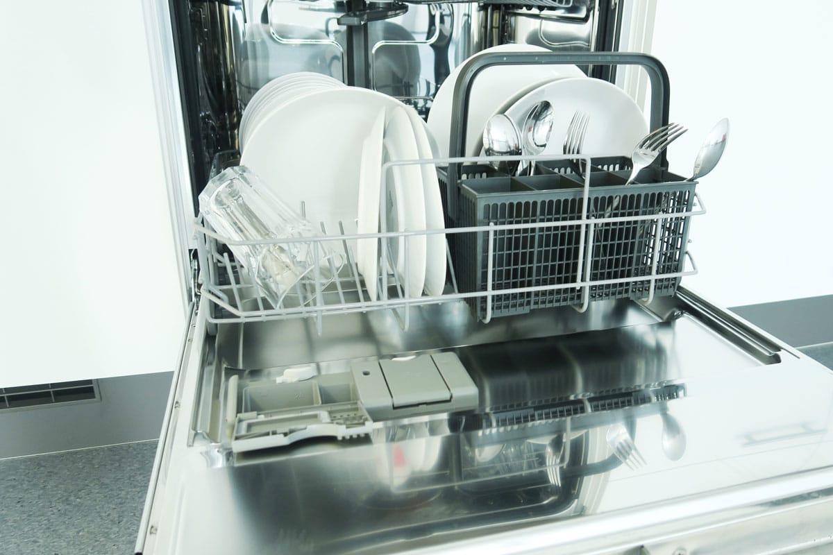 open diswasher with clean white dishes in a white kitchen
