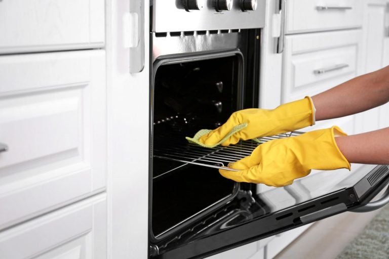 Woman cleaning oven in kitchen - How to Clean Oven When Aqualift Doesn't Work [Step by Step Guide]