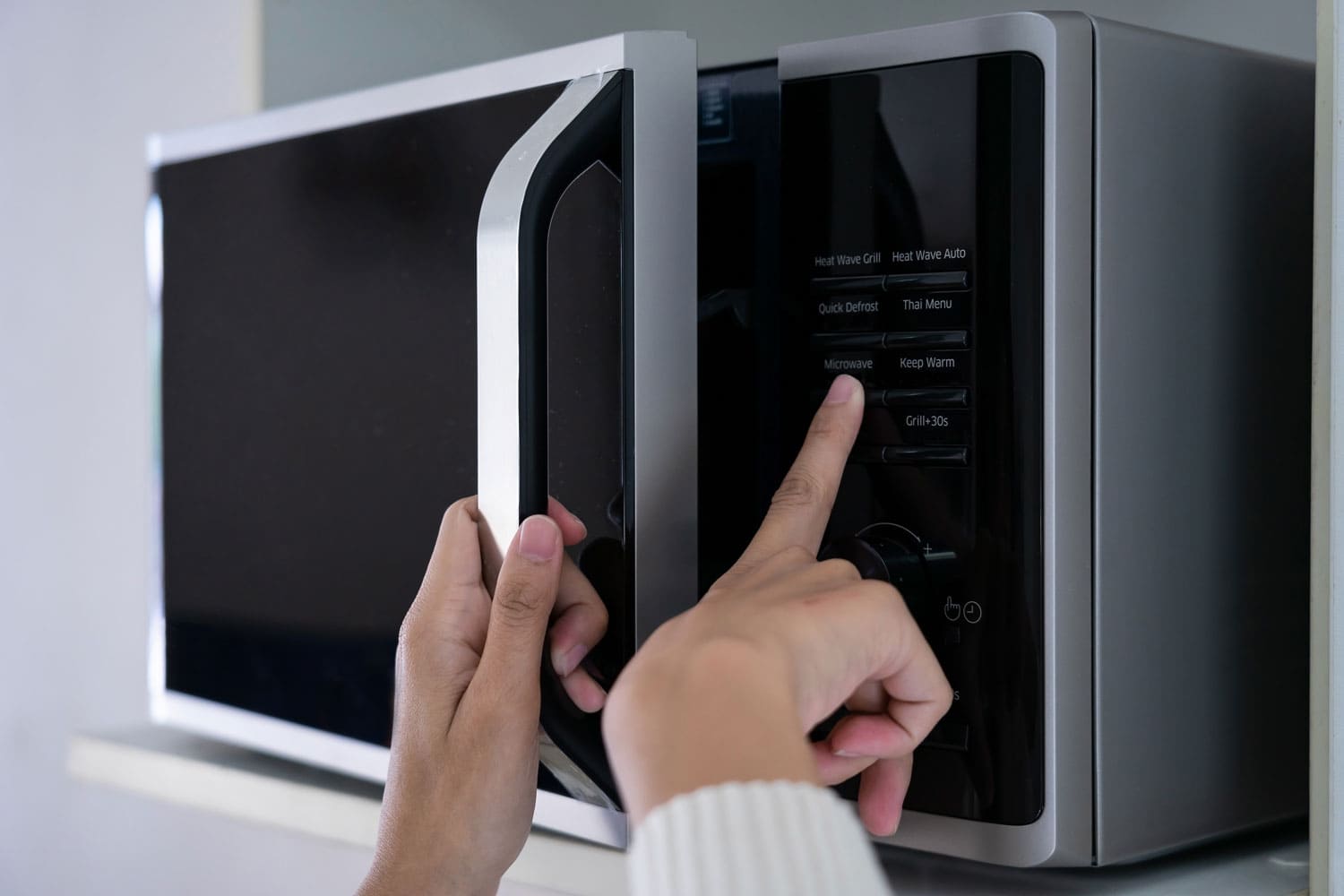 Woman's hand trying to use a Panasonic Microwave even if the clock is not set